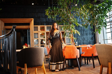 Pretty indian girl in black saree dress posed at restaurant.