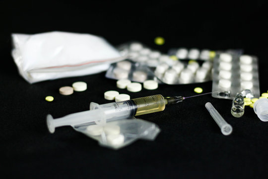 Drugs on a black background. Syringe, needle, pills, white powder, candle, spoon. Close up.