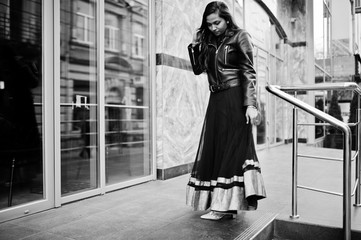 Fototapeta na wymiar Pretty indian girl in black saree dress and leather jacket posed outdoor at street.