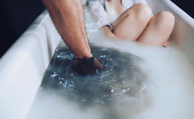 Fototapeta premium Black hands washes in the bathroom with a girl, on a dark background