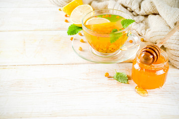 Homemade buckthorn, Hippophae, mint and honey tea wooden background copy space top view