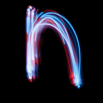 Letter N of the alphabet made from neon sign. The blue light image, long exposure with colored fairy lights, against a black background