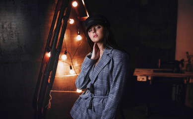 Portrait of girl on a dark background. Holds a cap a hand