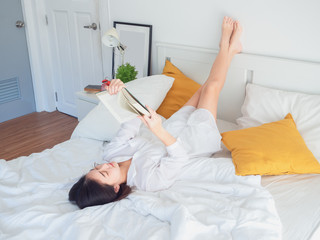 asian woman reading book on bed in the morning