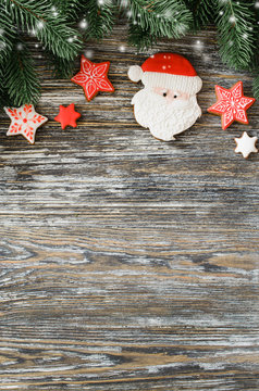 Christmas wooden background with fir tree and gingerbread Santa.