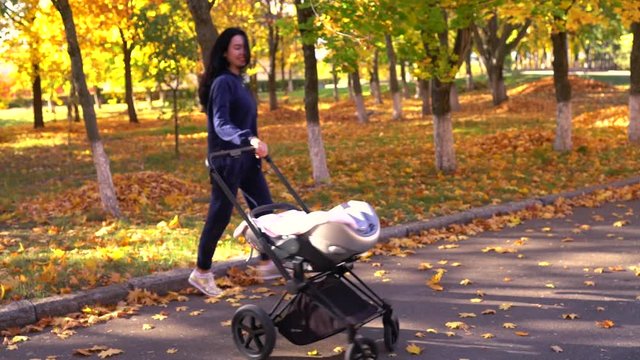 Young mother jumping around baby stroller
