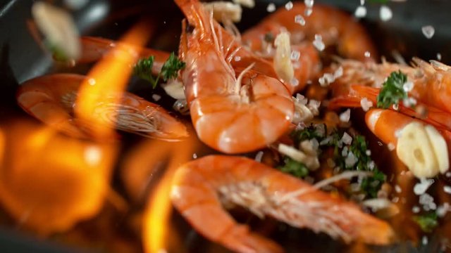 Super slowmotion footage of throwing fresh prawns and seasoning on ignited pan, 1000fps 4k
