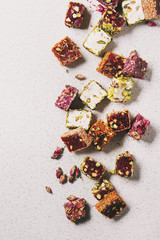 Variety of traditional turkish dessert Turkish Delight different taste and colors with rose petals and pistachio nuts over grey spotted background. Flat lay, copy copy space