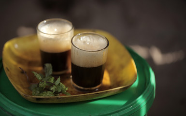 close up of traditional african tea - black strong green attaya in small glasses on a yellow plate, outdoors in the Gambia, Africa