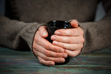 Woman holds a cup of hot tea. Cozy morning at home.