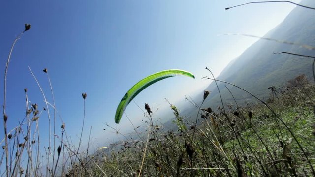green paraglider starting a flight from the ground to the sky