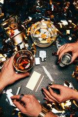 cropped image of couple celebrating with cocaine, alcohol and cigarettes at table covered by golden...