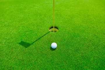 Photo sur Plexiglas Golf balle de golf dans l& 39 herbe verte près du trou avec l& 39 ombre du mât