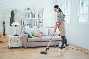 young housewife using vacuum cleaner cleaning