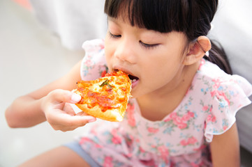 young asian girl enjoy eating pizza