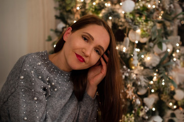 portrait of a young girl in a knitted dress by the Christmas tree