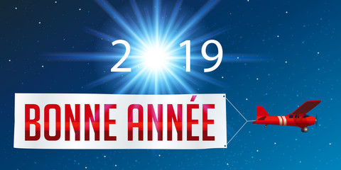 Carte de vœux 2019 montrant un avion rouge tirant une banderole blanche pour souhaiter la bonne année, devant un ciel étoilé