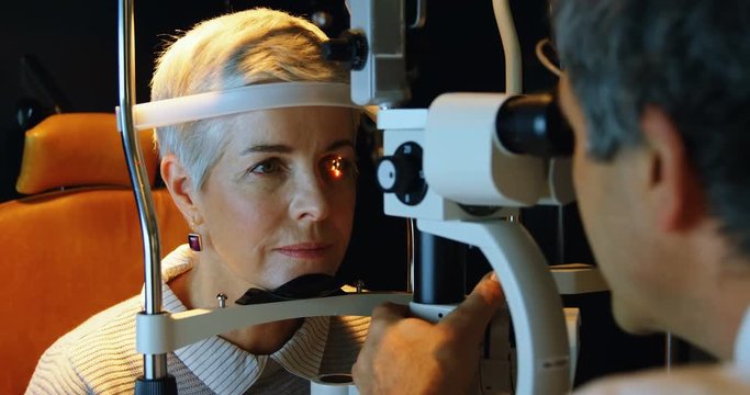 Optometrist examining patient eyes with slit lamp 4k