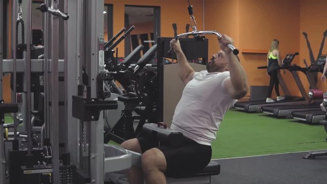 Bodybuilder doing exercise on simulator in gym. Exercises for chest and back muscles in slow motion
