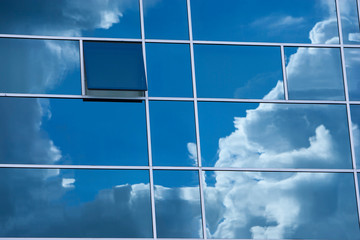 ventanal de cristal donde se refleja un cielo con nubes, y ventana abierta
