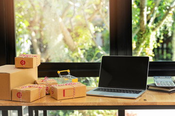 Cardboard parcel box and laptop ondesk at workplace of startup small business owner for online selling.