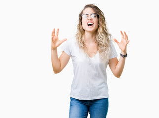 Fototapeta na wymiar Beautiful young blonde woman wearing glasses over isolated background crazy and mad shouting and yelling with aggressive expression and arms raised. Frustration concept.
