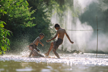 Asian children play soccer in the river,Sport plays an important role in rural and regional...