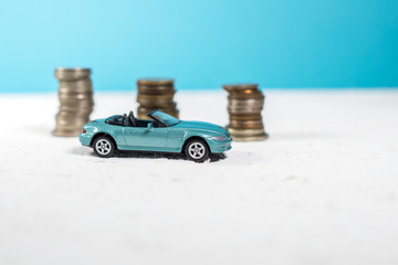 toy blue car cabriolet on a white road. behind lie money