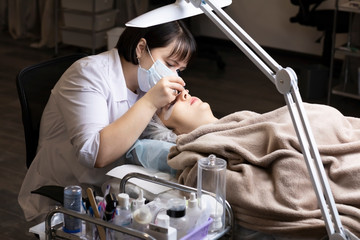 Eyelash extension procedure . Master and a client in a beauty salon