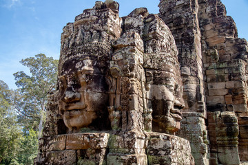 Fototapeta premium Ancient temple name Bayon with stone faces in Angkor Thom, Siem Reap, Cambodia. Bayon's most distinctive feature is the multitude of serene and smiling stone faces on the many towers.