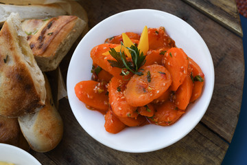 Spicy carrot salad in white bowl on wooden background
