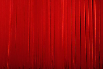 Bright red theater curtain made of velvet fabric. Background.