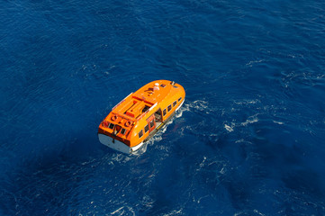 Orange rescue boat on blue sea waves background. Aerial view