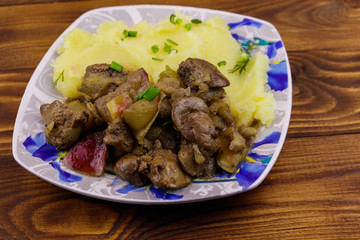 Mashed potatoes with stewed chicken liver with apple and onion on wooden table