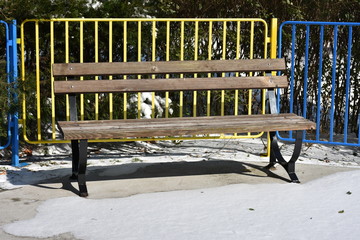 a wooden bench in the park and snow