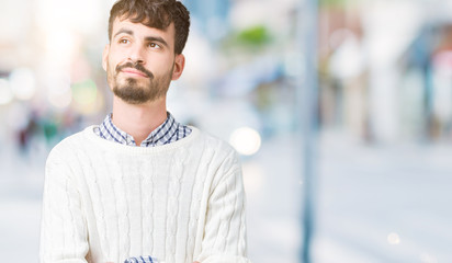 Young handsome man wearing winter sweater over isolated background smiling looking side and staring away thinking.