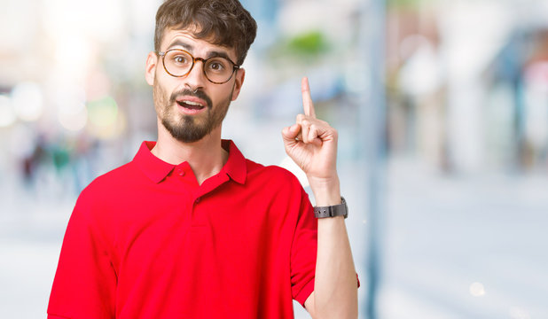 Young handsome man wearing glasses over isolated background pointing finger up with successful idea. Exited and happy. Number one.