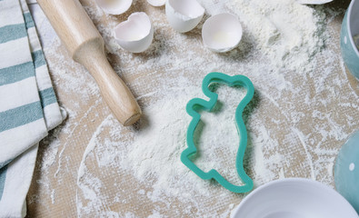 Table with shapes for cookies, flour, napkin, raw eggs, preparation before baking. Top view flat lay with space for text, mockup for recipe or cooking blog.