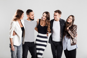 Fototapeta premium Company of friends in fashionable casual clothes stand together and talk on a white background in the studio
