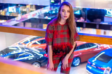 Portrait of a young girl who buys a new car in a car salon.