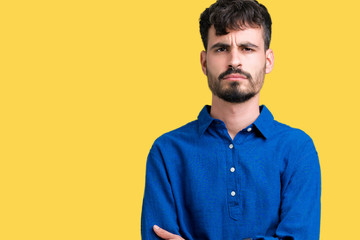 Young handsome man over isolated background skeptic and nervous, disapproving expression on face with crossed arms. Negative person.