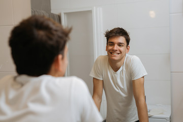 teenager boy in bathroom looking at mirror