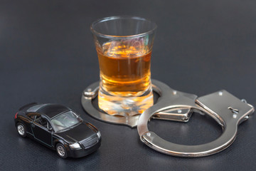 alcohol Whiskey with model car and handcuffs. concept for drinking and driving. police caught drunk driver