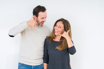 Beautiful middle age couple in love over isolated background smiling doing phone gesture with hand and fingers like talking on the telephone. Communicating concepts.