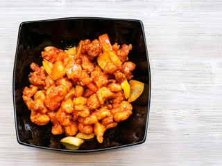 Sweet and Sour Chicken in black bowl on gray table
