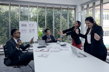 Male executive and other staff listening music and dancing in meeting room during sale report discussion; relaxation to release stress concept