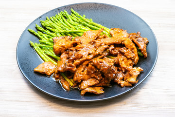 fried Beef with green asparagus on black plate
