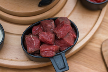 Eine Schüssel Rindfleisch in Stücke auf einer hölzernen Platte, die zum Fondue bereit ist