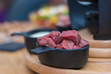 Eine Schüssel Rindfleisch in Stücke auf einer hölzernen Platte, die zum Fondue bereit ist