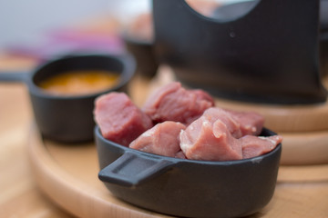 Eine Schüssel Schweinefleisch in Stücke auf einer hölzernen Platte, die zum Fondue bereit ist